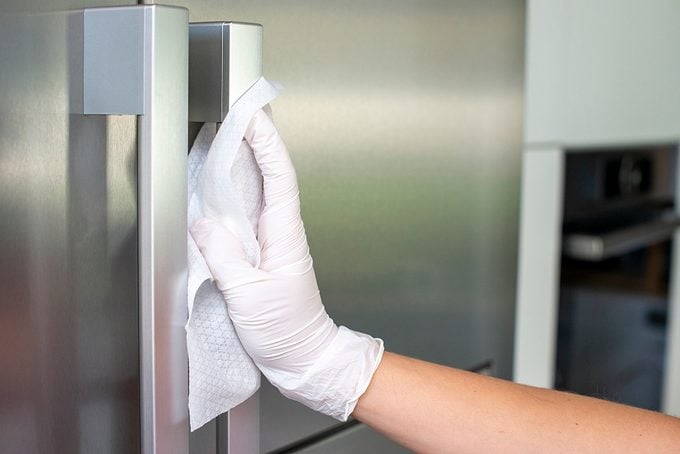 Woman Cleans refrigerator Handle Using Disinfectant Wipe