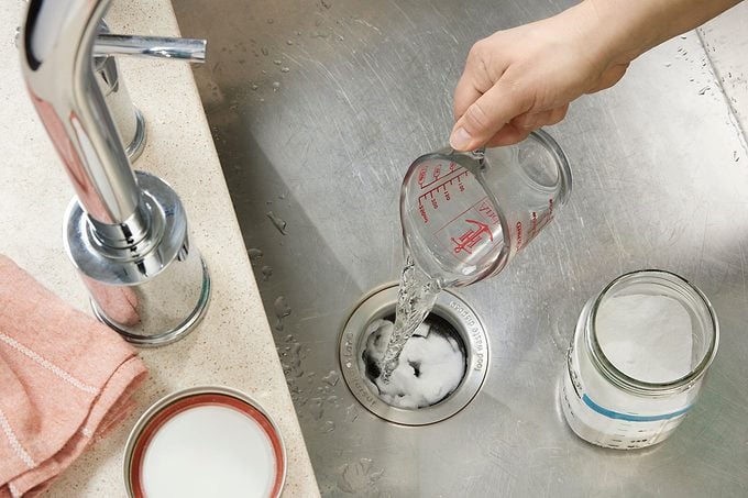 Hand Pouring Boiling Water Into Drain to create bubbling with drain cleaner already in drain