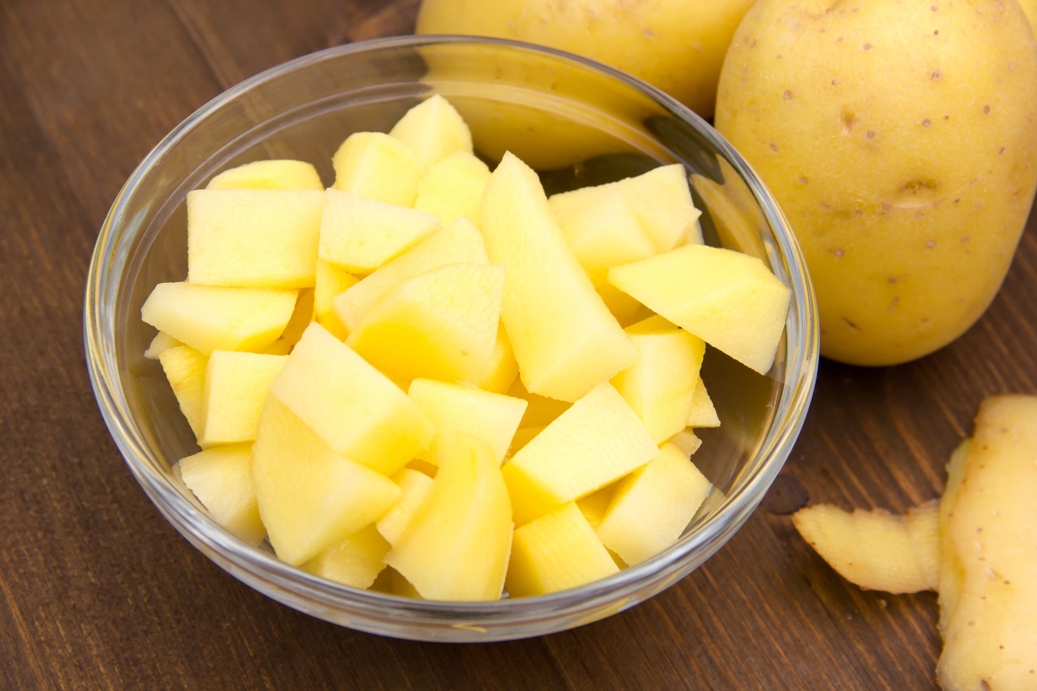 Bowl with potato cubes on wood