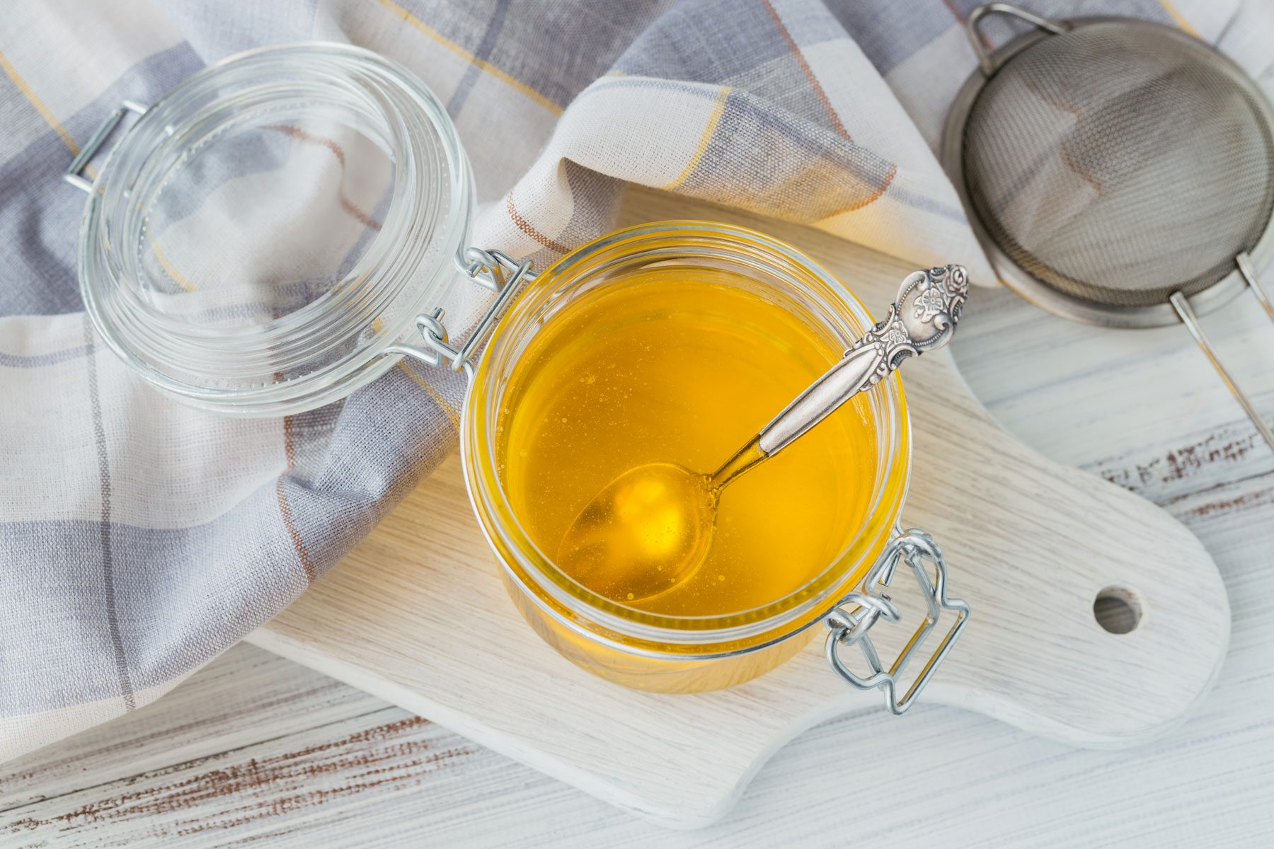 homemade Ghee or clarified butter in jar on white wooden table