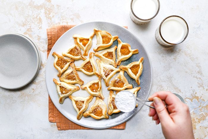 Dusting the confectioners' sugarApricot Filled Triangles served on a plate.