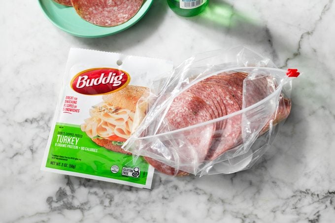 Pre-packaged and deli counter lunch meat packages on a marble countertop