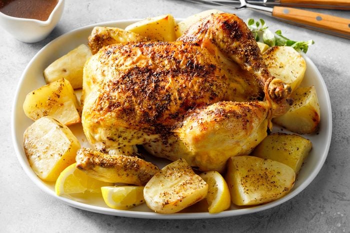 Greek Chicken And Potatoes Served on an oval shaped plate on marble surface
