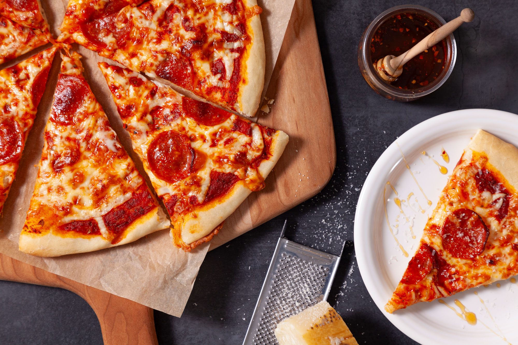 Homemade Pizza on a wooden pizza server and a slice of it on a small plate next to it