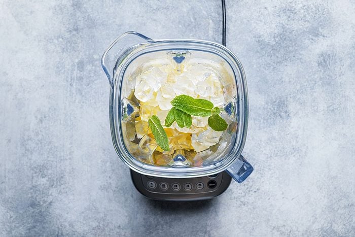 Yogurt, mango, ice, sugar, mint combined in a blender to make mango lassi