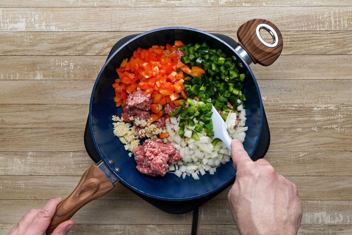 Cooking beef with onion, peppers and garlic in a large skillet