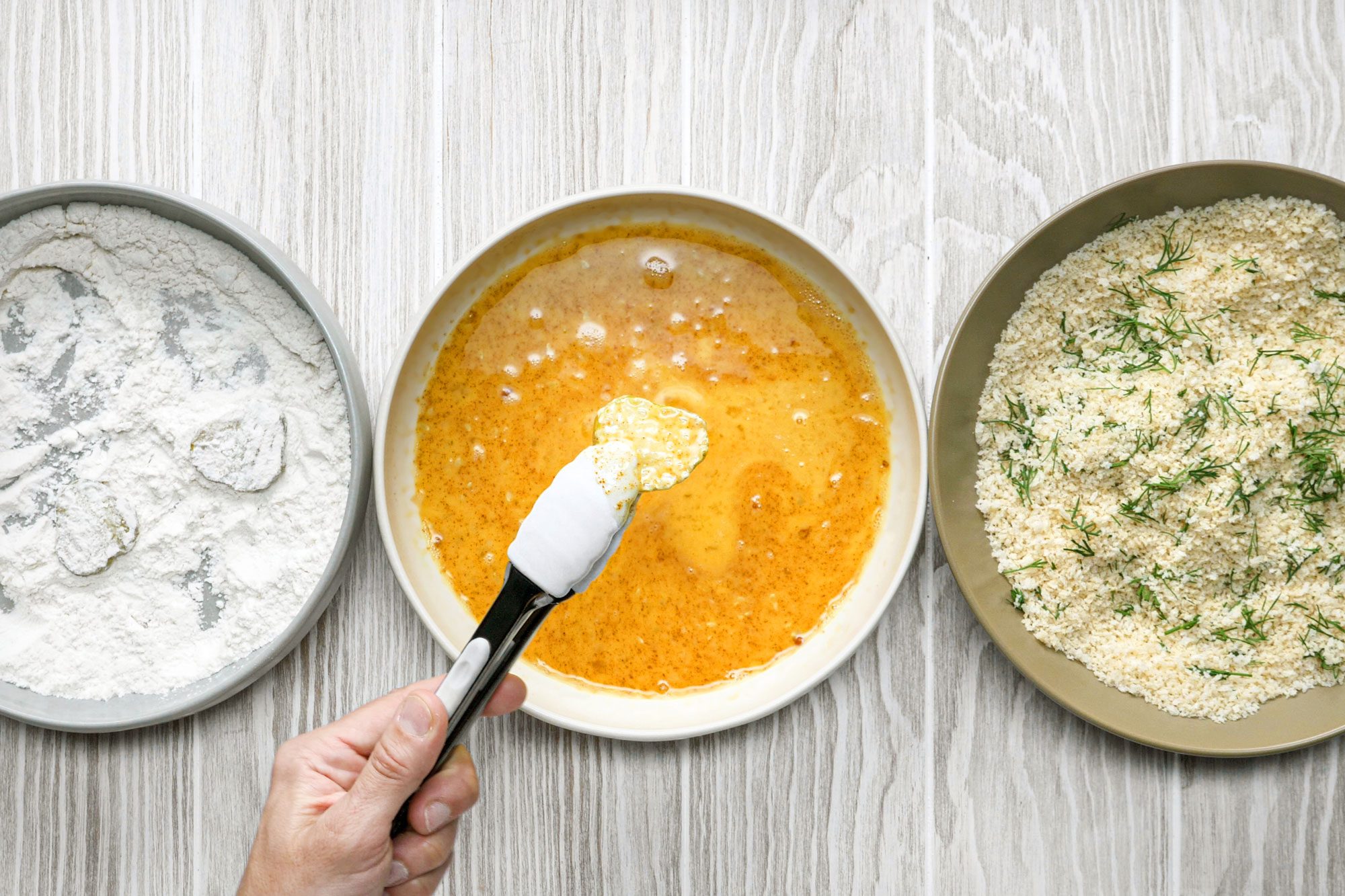 overhead shot of dill pickle slices dipped in egg mixture; flour mixture;