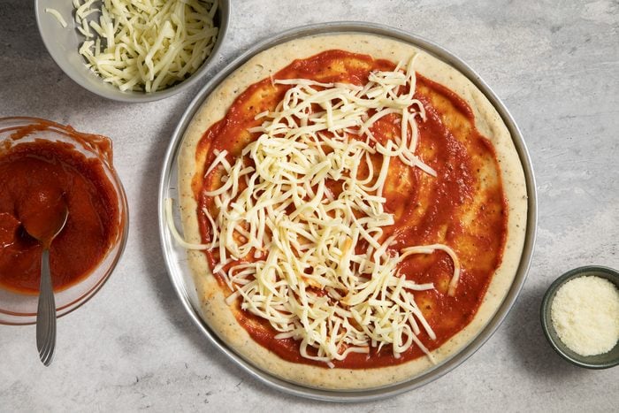 A pizza in pizza pan with cheese on it