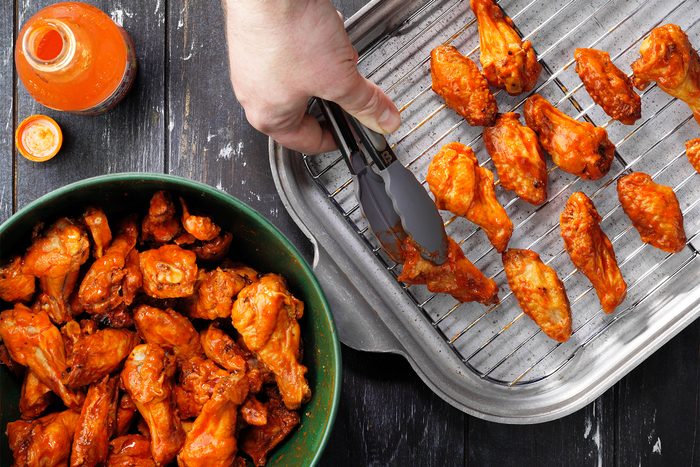 A person cooking chicken wings