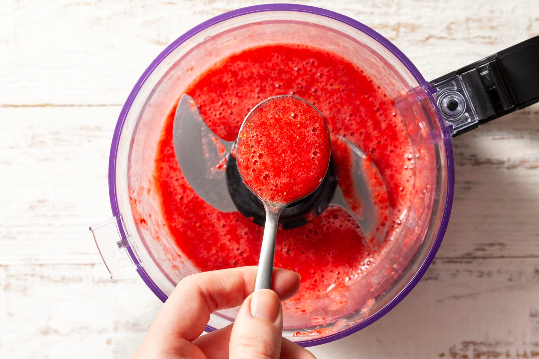 A hand holding a spoon with blender