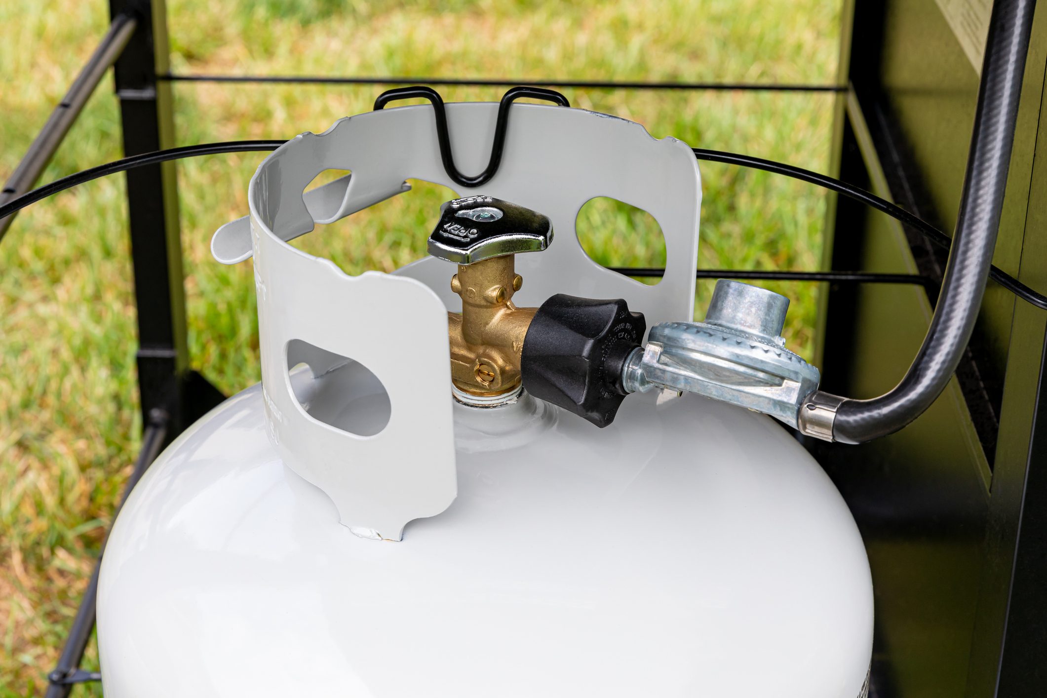 Propane gas cylinder with hose and regulator for BBQ grill. Grilling safety, LPG equipment inspection and storage