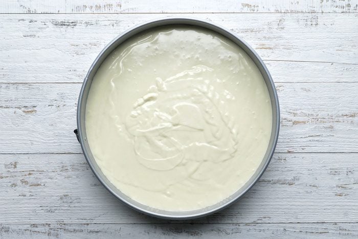 Overhead shot of pan; spread mixture over crust; wooden background;