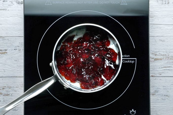 Overhead shot of a saucepan; combined cornstarch and water until smooth; add jelly and cook; stirring constantly until jelly is melted and mixture has thickened; wooden background;