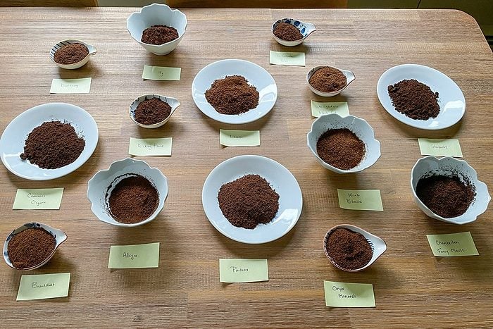 Different Coffee Grounds in small bowls on wooden table with labels in front of them