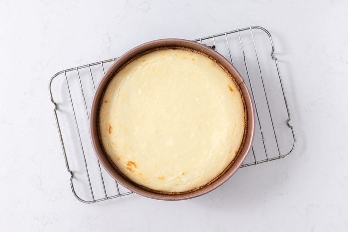 Cheesecake baked and cooling in wire rack.