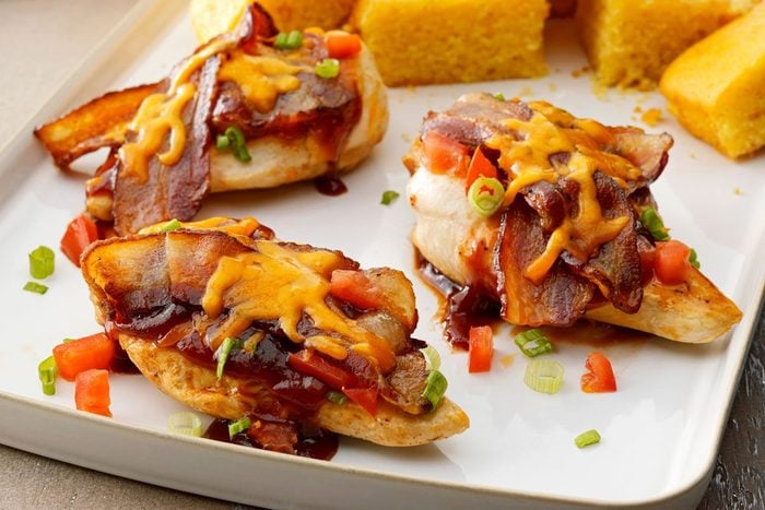 Close up of Monterey Chicken on a tray drizzled with sauce and topped with cheese