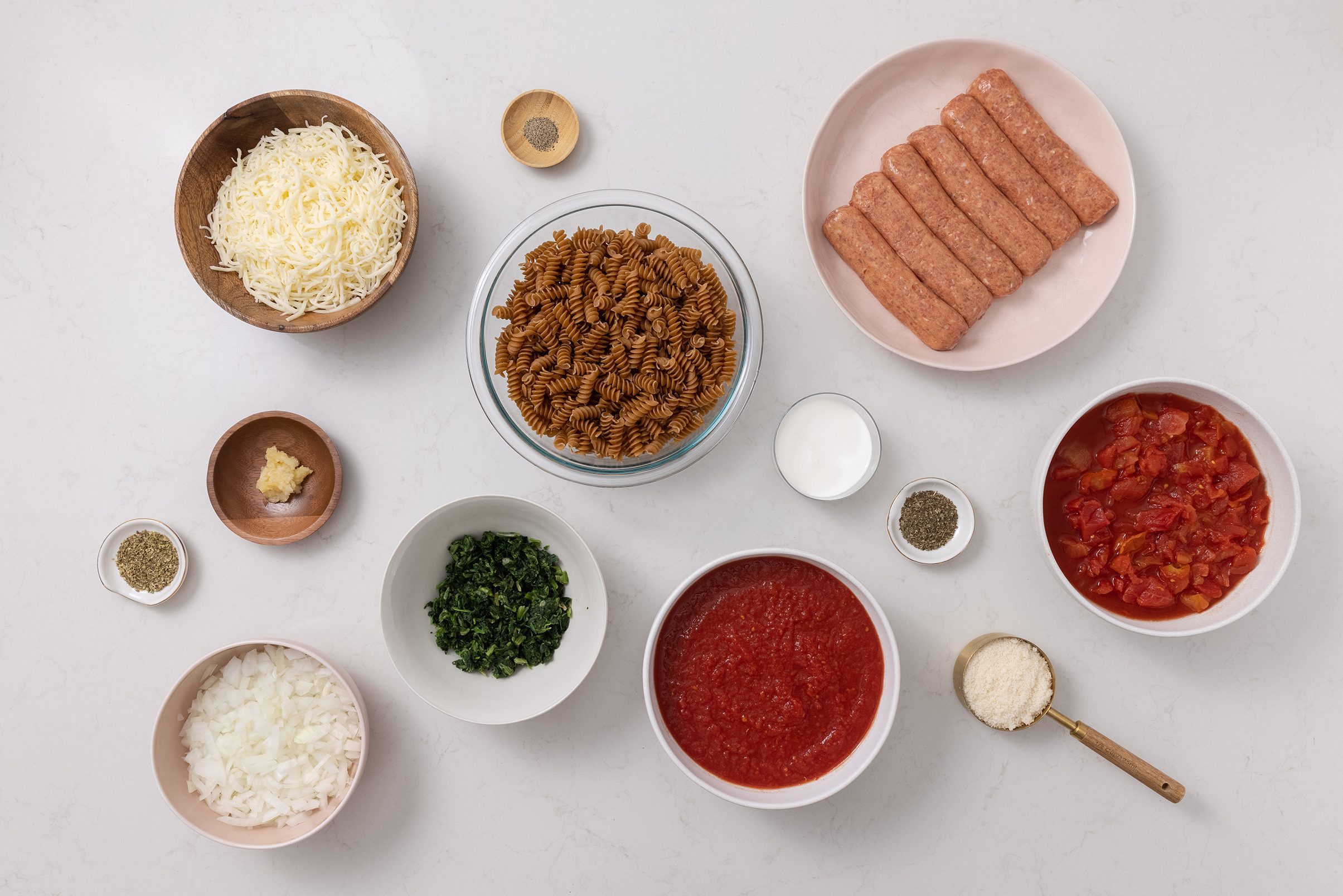 Ingredients for spinach sausage pasta bake on kitchen counter.