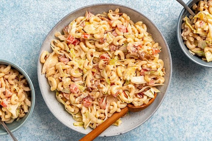 overhead shot of BLT Pasta Salad in a large bowl with small portions in two smaller bowls next to it