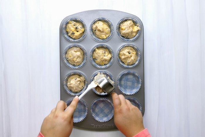 Filling greased paper-lined muffin cups three-fourths full