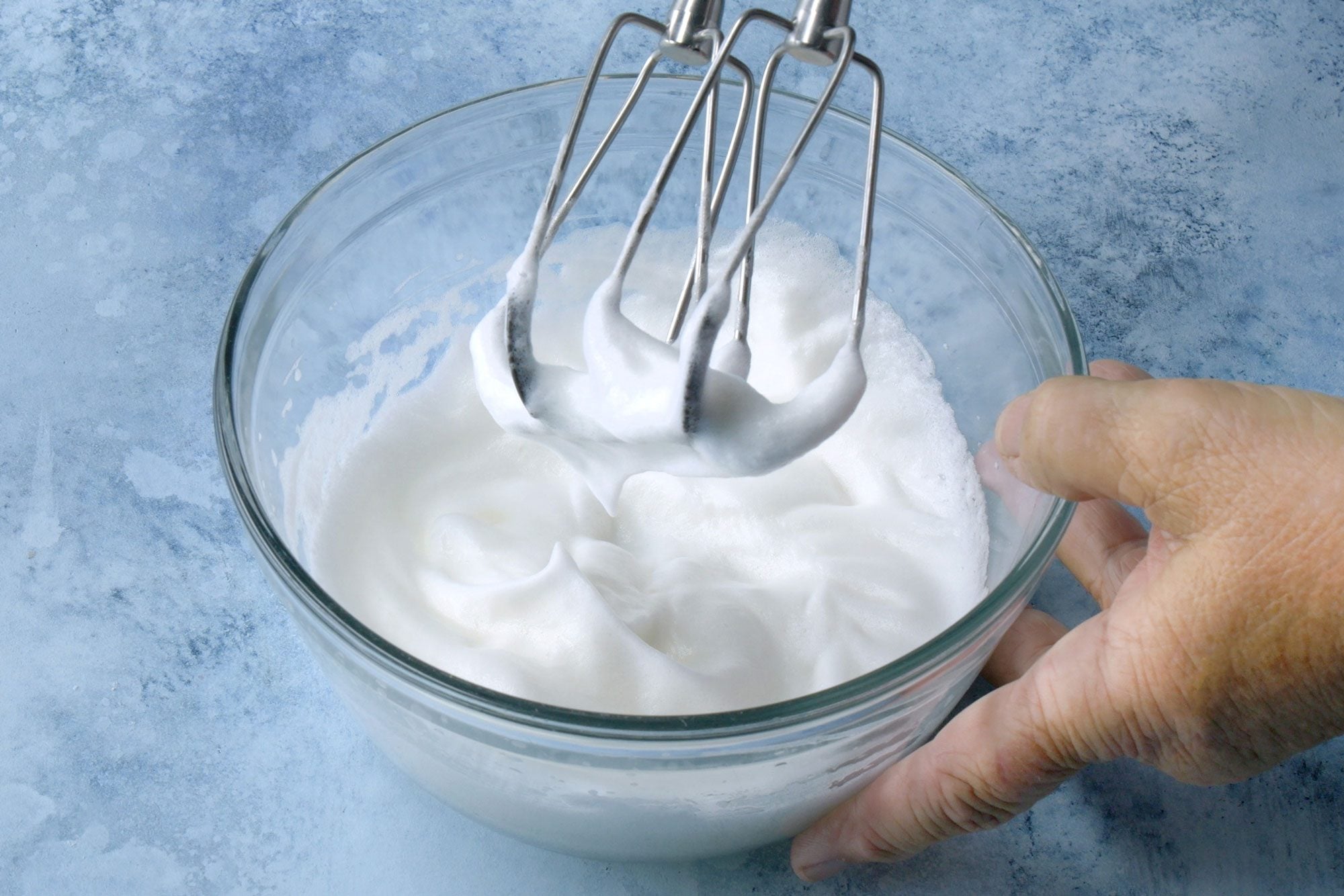 3/4th shot; light blue background; In a small bowl, beating egg whites until stiff peaks form;