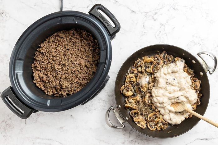 Taste of Home Crock Pot Tater Tot Casserole recipe photo of ground beef in the crockpot while the onion, mushrooms, garlic and condensed soup are in a skillet.