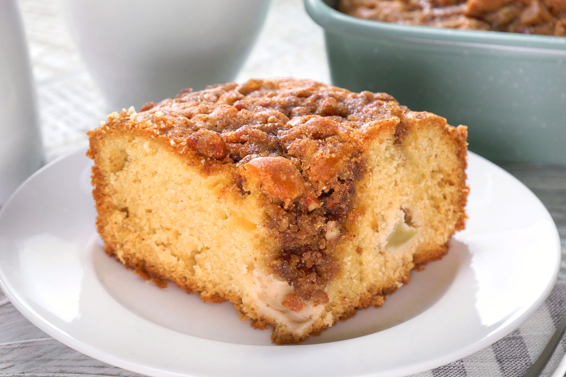 A piece of sour cream apple cake on a white plate.