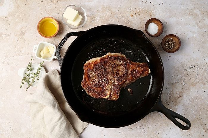 A how to look into Taste of Home's homemade Steak Frites. Steak in a cast iron pan with butter, garlic and thyme.