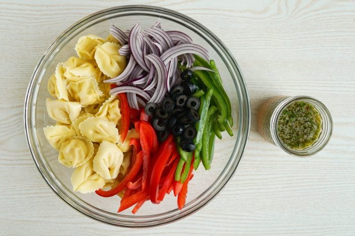 Tortellini pasta salad ingredients and dressing ready to be tossed