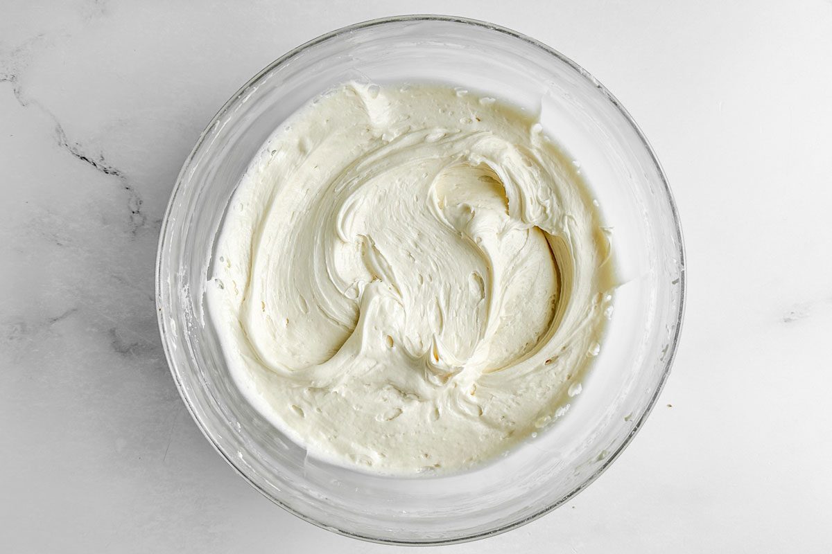 Buttercream for Taste of Home Amaretto Cake in a glass bowl on a marble surface