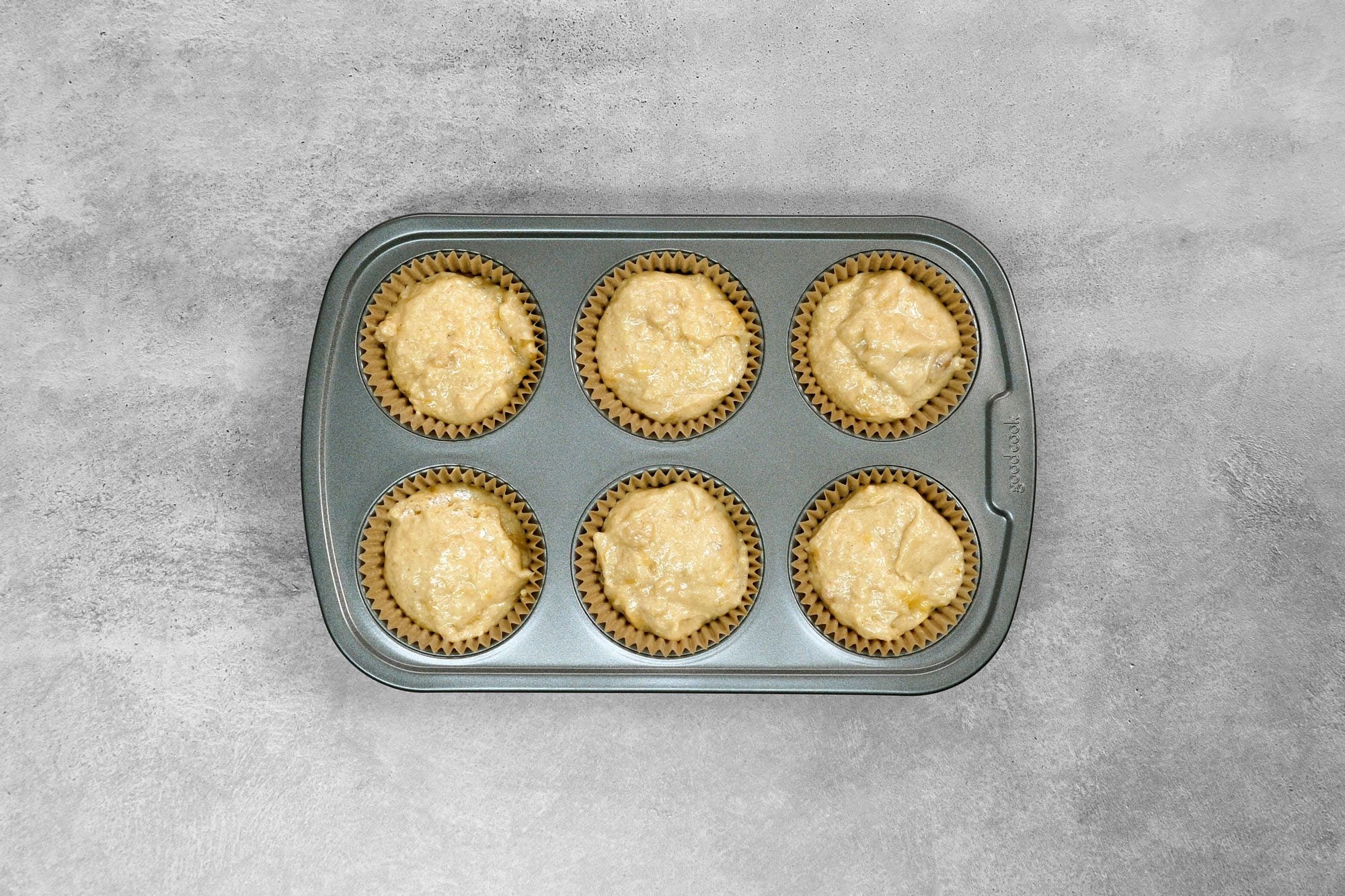 overhead shot; grey background; filled muffin cups two-thirds full with batter;