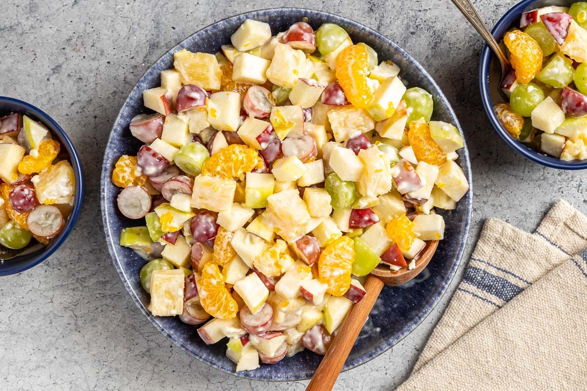 overhead shot of Cream Cheese Fruit Salad in a large serving bowl next to small portions in two smaller bowls