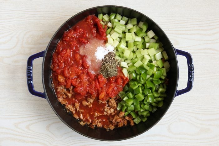 Adding vegetables and seasoning to soup