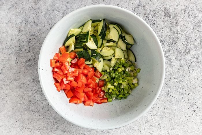 Taste of Home Linguine Salad recipe photo of the tomatoes, cucumber and the green onions in a mixing bowl.