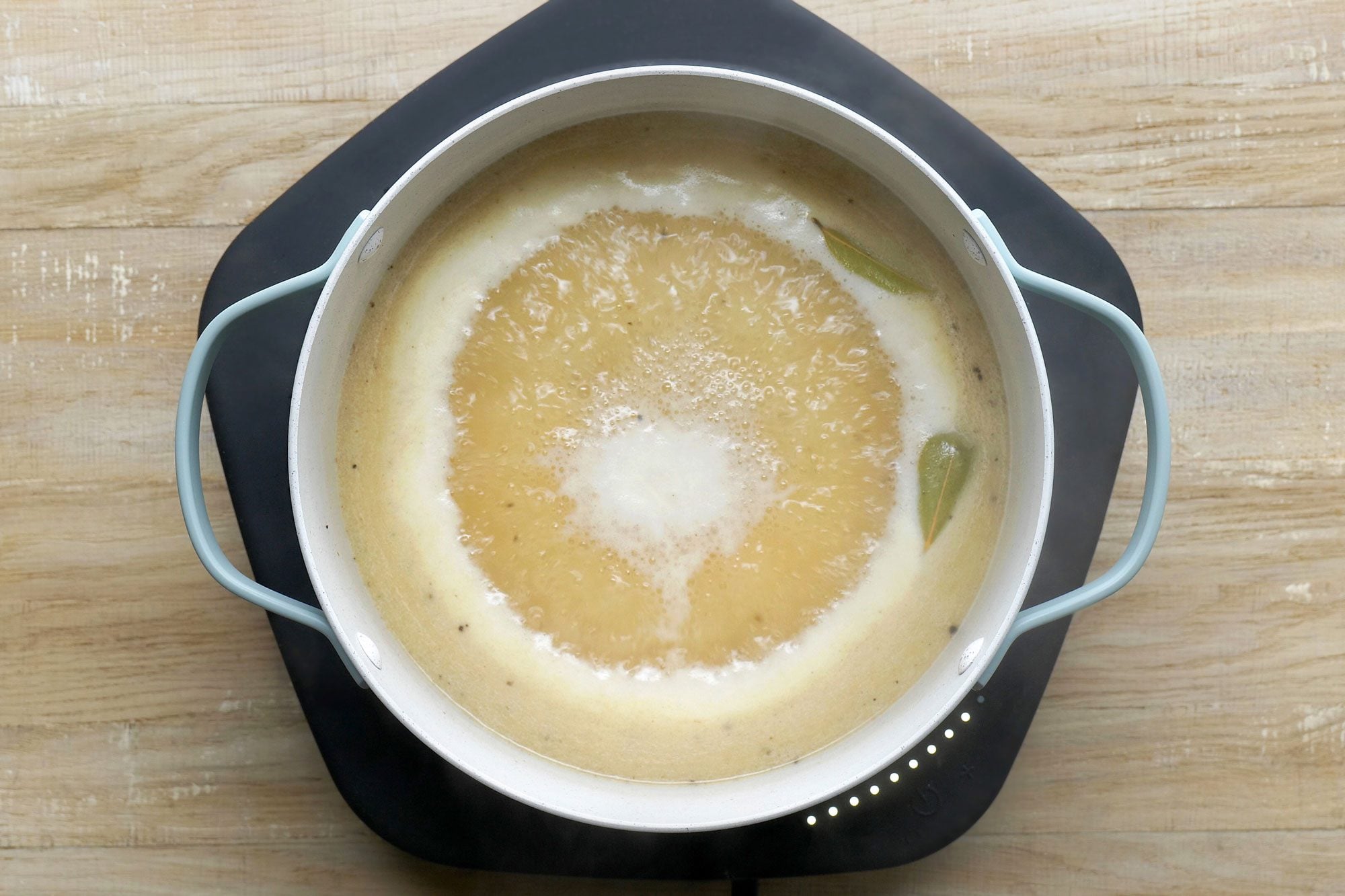 overhead shot; wooden background; added in broth, Stir in the bay leaves, salt, pepper, pepper sauce, Worcestershire sauce and nutmeg and boiling;