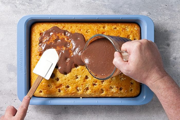 Overhead shot of a small bowl whisk milk and pudding mix 2 minutes; immediately spread into holes and over top of cake; refrigerate 30 minutes; spatula; grey surface