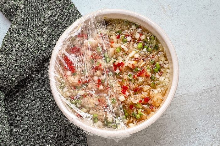 Saurkraut salad preparation, showing plastic wrap covering the bowl.