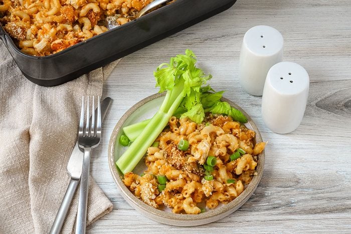 A serving of Buffalo chicken mac and cheese with fresh celery sticks on the side.