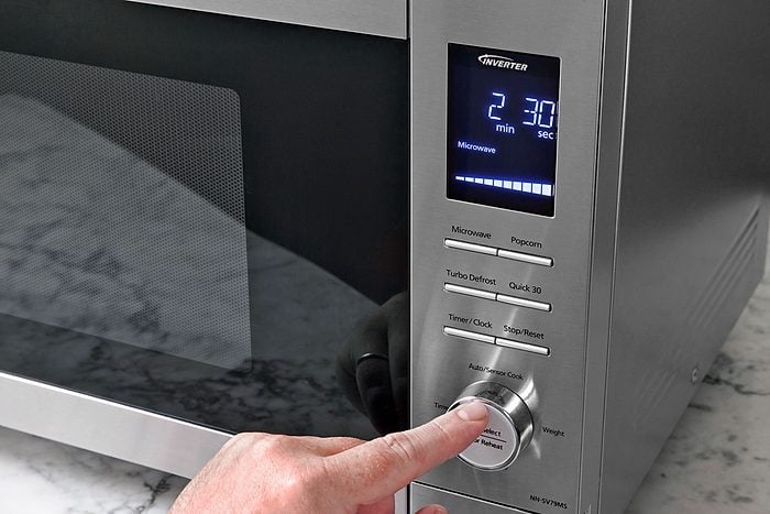 A hand can be seen adjusting microwave settings.