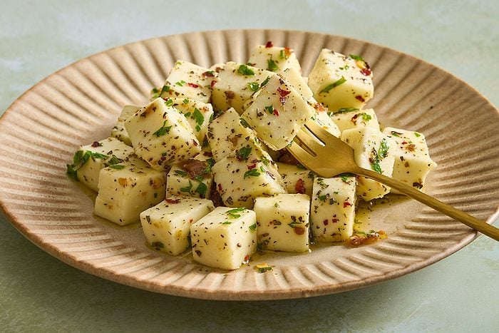 Cloesup of a plate full of marinated mozzarella with one piece skewered onto a fork