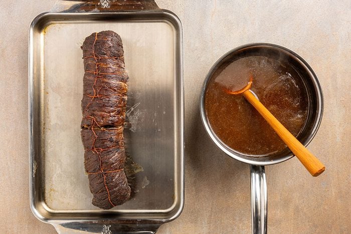 rolled and cooked flank steak with side of sauce.