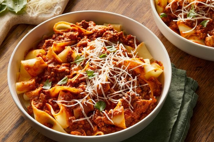 Pappardelle Bolognese served in a bowl on a wooden table