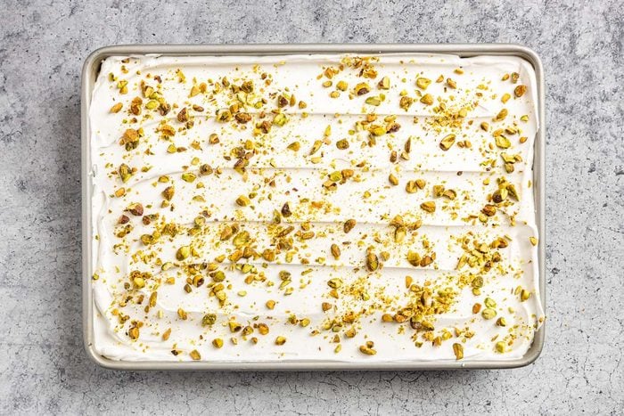 Taste of Home Pistachio Pudding Dessert photo of the whipped topping layer with chopped pistachios.