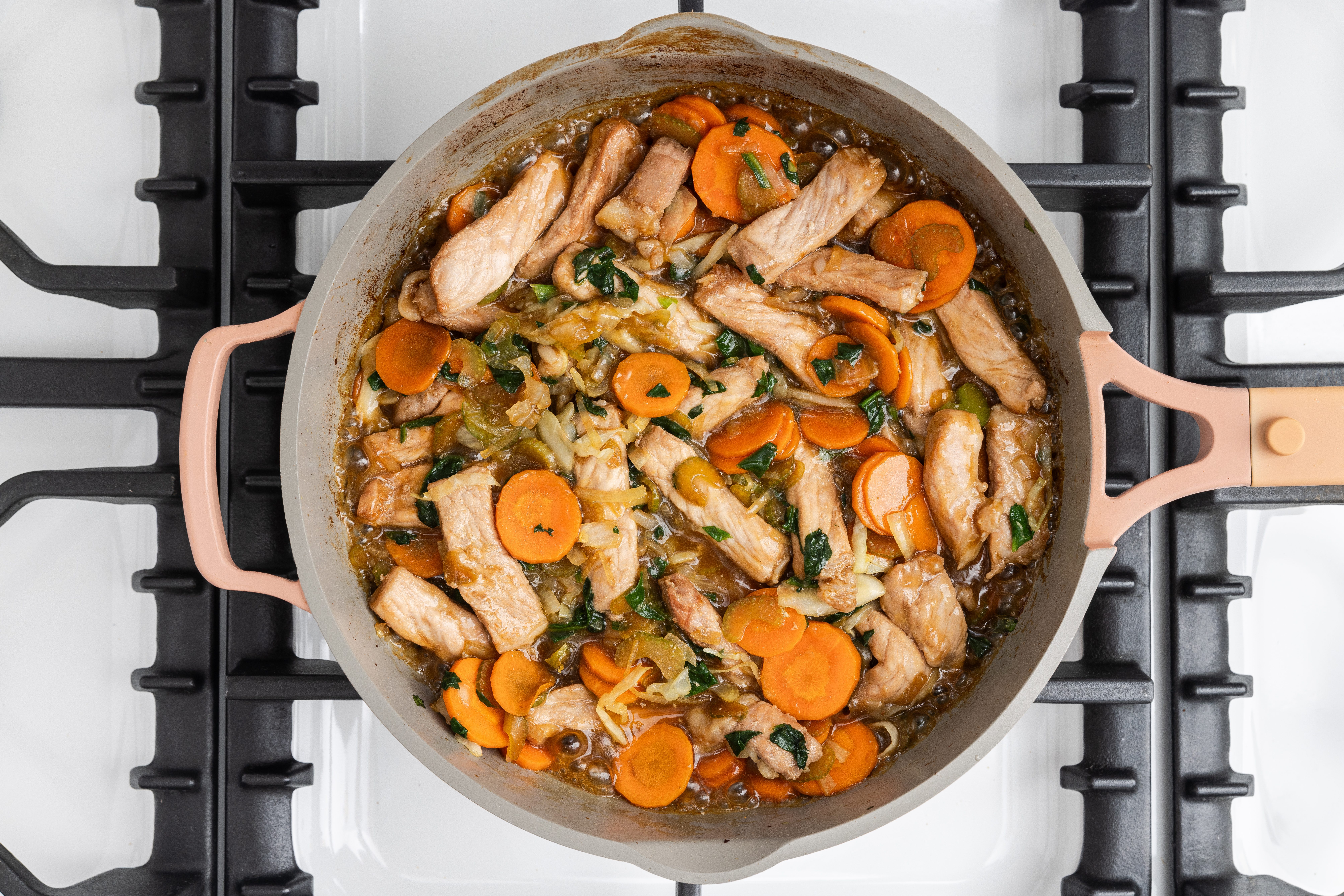 Pork loin and vegetables combined with sauce in skillet.