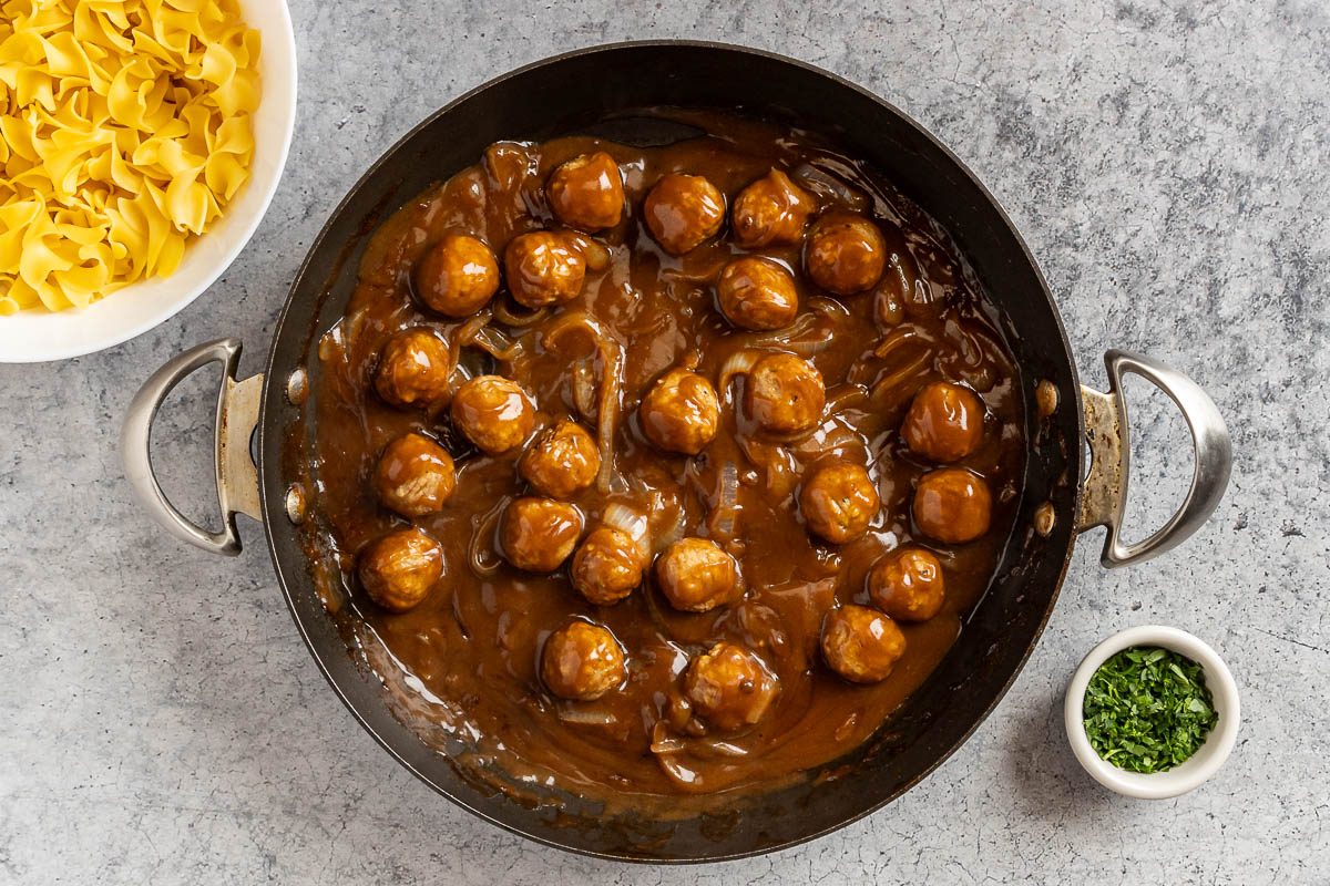 Taste of Home Salisbury Steak Meatballs photo of the prepared meatballs with a side of egg noodle and parsley.