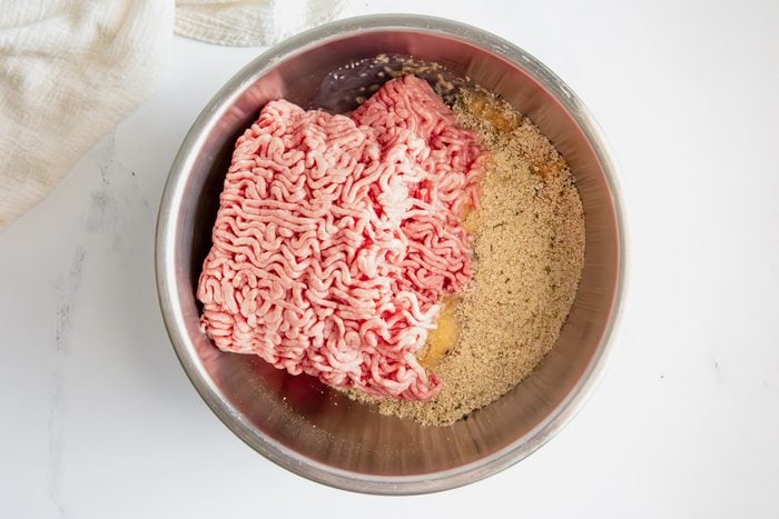 Overhead shot for Taste of Slow-Cooker Spaghetti and Meatballs, meatball ingredients in a metal bowl before being mixed together.