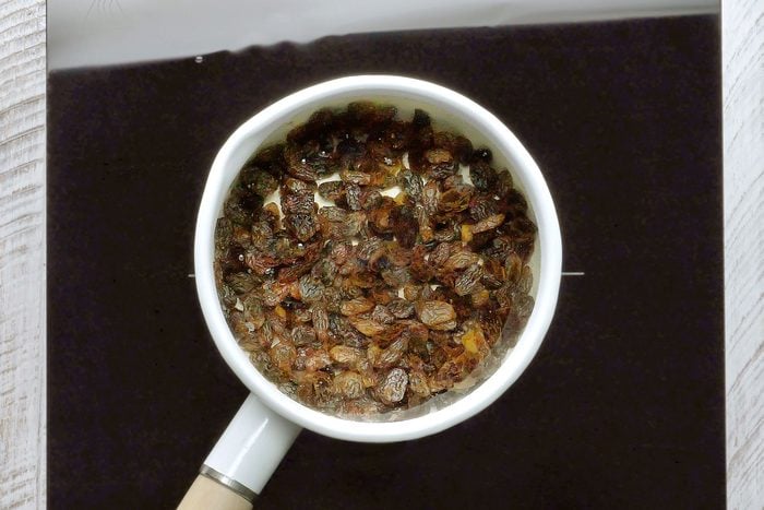 Raisins boiling in water in a small saucepan.