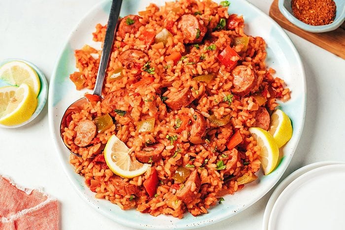 Spanish rice with sausage recipe by Taste of Home served on a large platter topped with chopped fresh parsley and lemon wedges