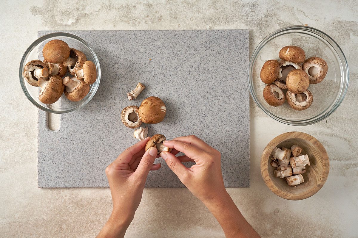 Sorting, cleaning, and removing the stems from mushrooms to prepare for stuffing, for the Stuffed Mushrooms with Crabmeat recipe, by Taste of Home.