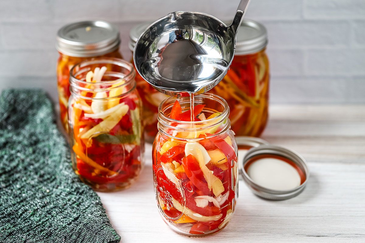 Filling jars with canning liquid for pickled sweet peppers.