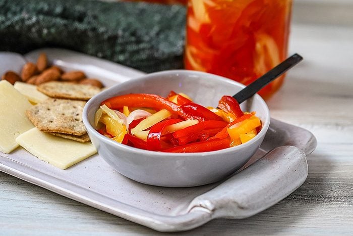 Sweet pickled peppers served with assorted crackers and cheese as a snack.